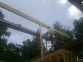 Carpenter setting a ridge beam over a new addition frame — Ice Dam Removal by Roofing Brothers in Marble