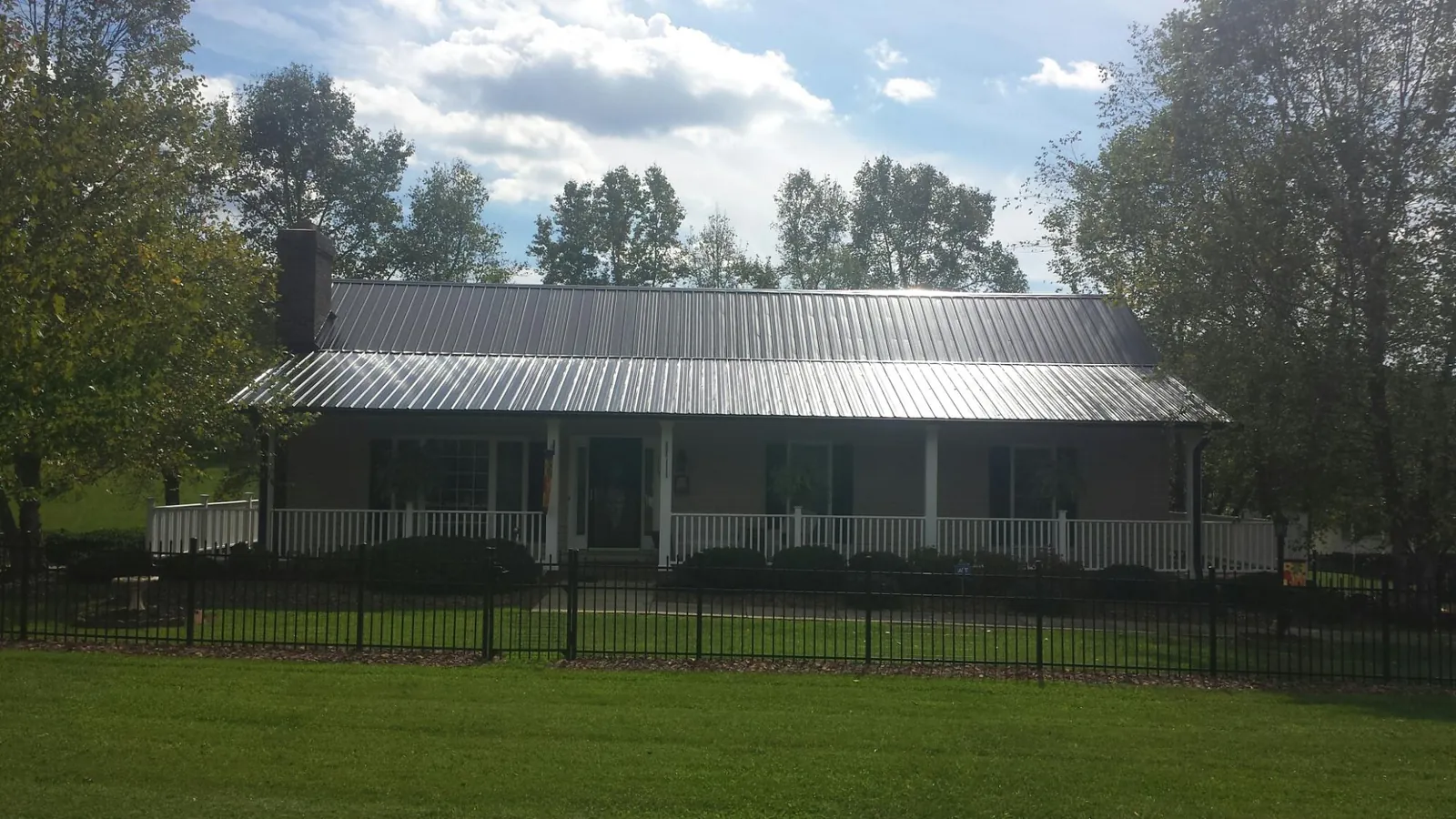 Gray metal roof on a brick ranch with a full width front porch — Gutter Guard Installation work by our crew in Marble