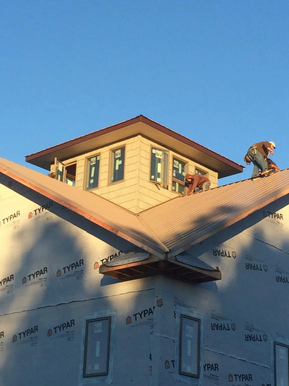 Roofers working around a rooftop cupola on a new metal roof at sunset — Roof Waterproofing in Marble by Roofing Brothers